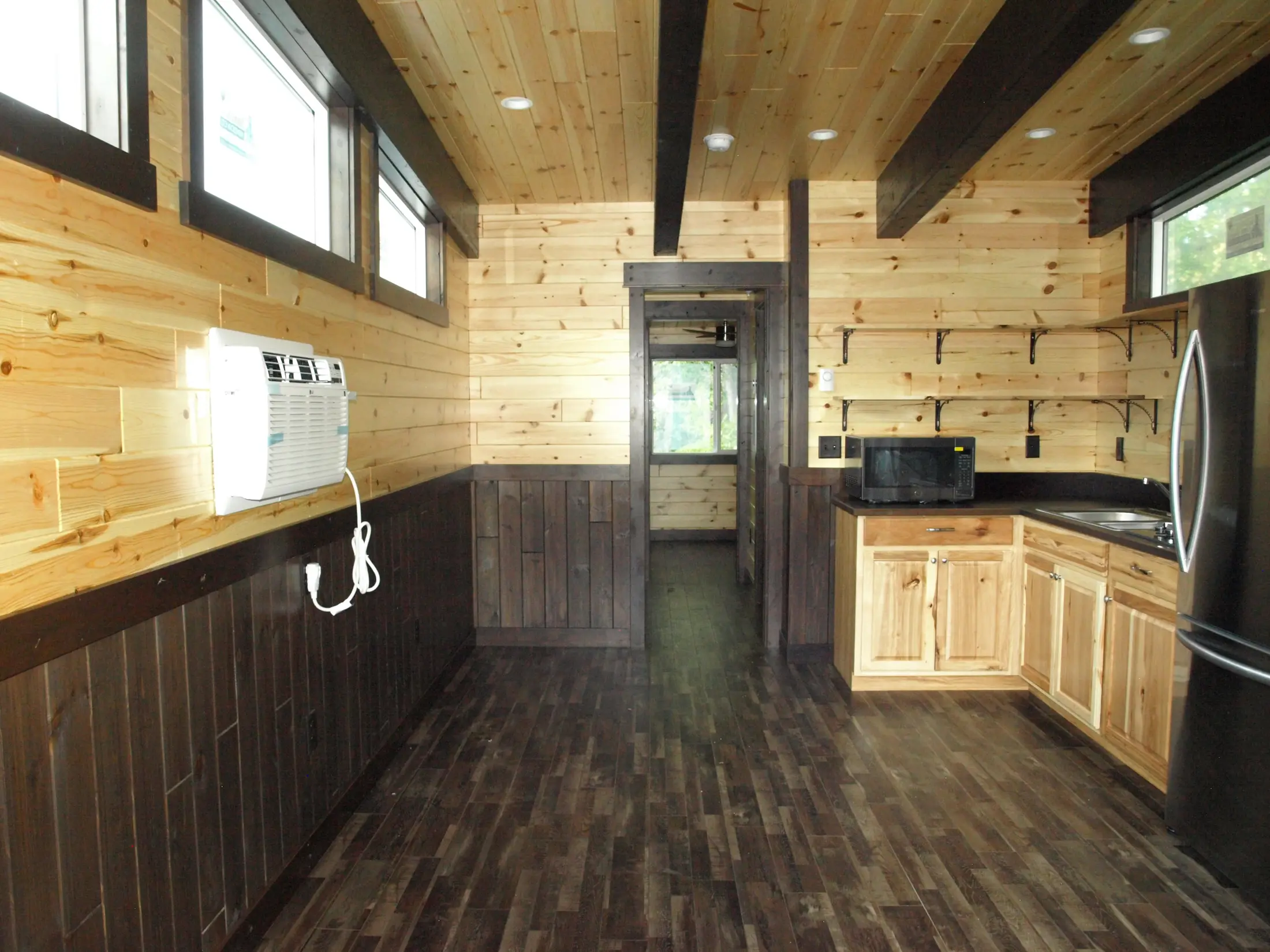 Knotty pine cabin kitchen with dark wainscot and exposed black beams