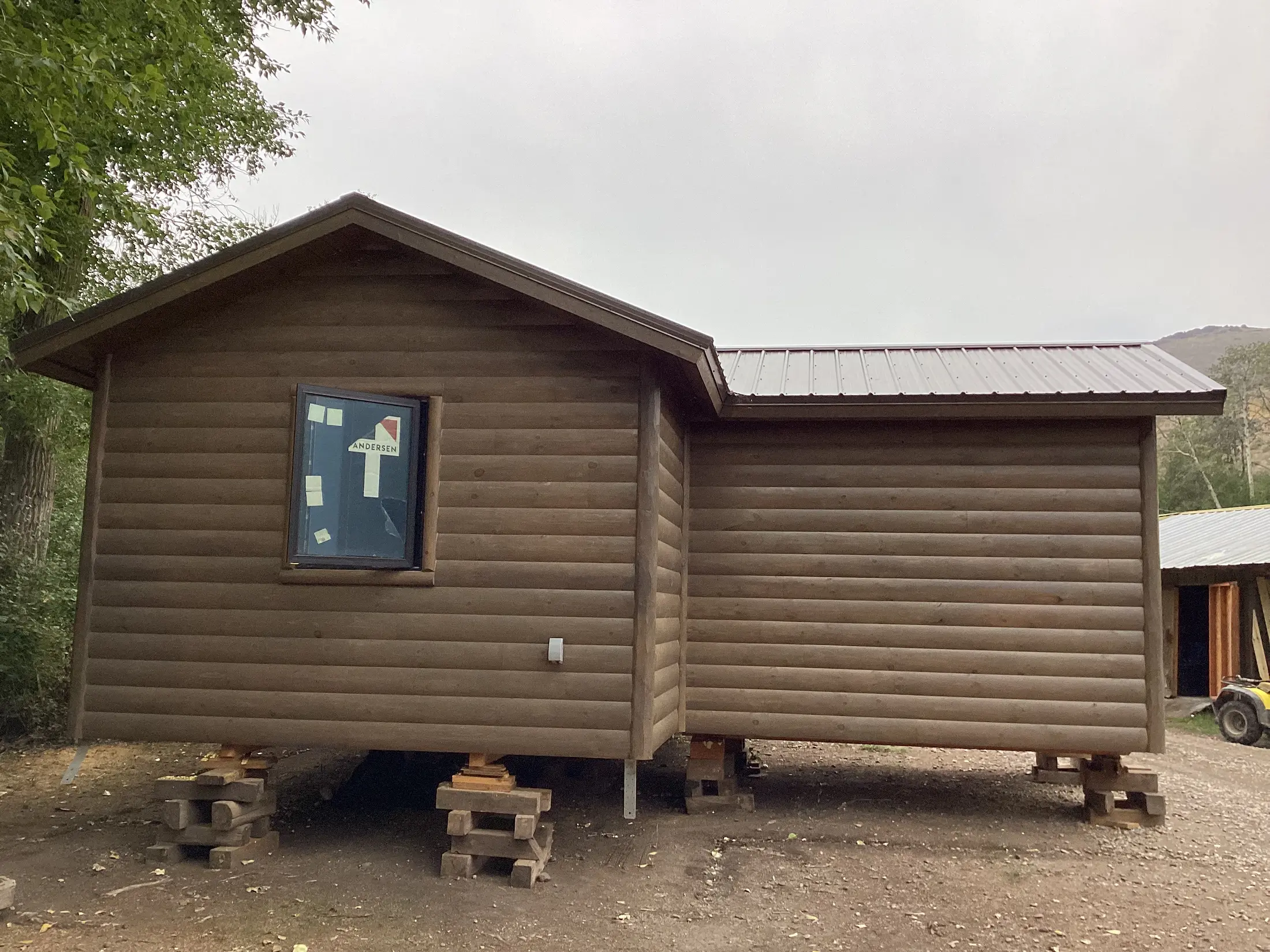 Teton Valley cabin section with log siding and a metal roof, blocked up in the build yard